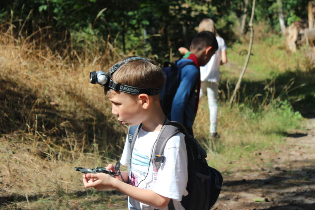 Kinder und Jugendliche nehmen während einer Wildfang-Ferienfreizeit an einer Orientierungswanderung teil – Teamarbeit und Abenteuer in der Natur