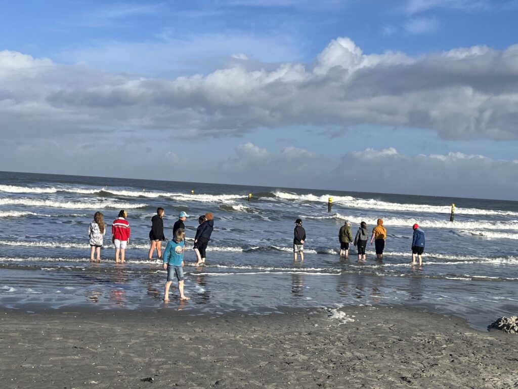 Kinder laufen barfuß am Strand von Norderney entlang