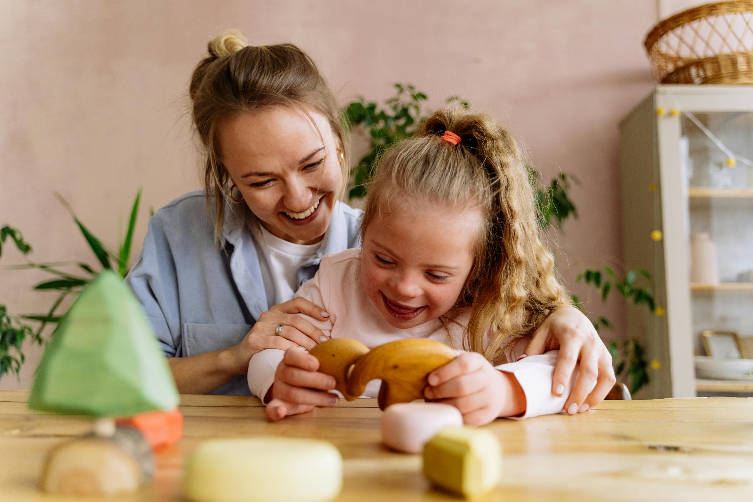 A joyful mother and daughter playing with wooden toys, sharing laughter and love indoors.