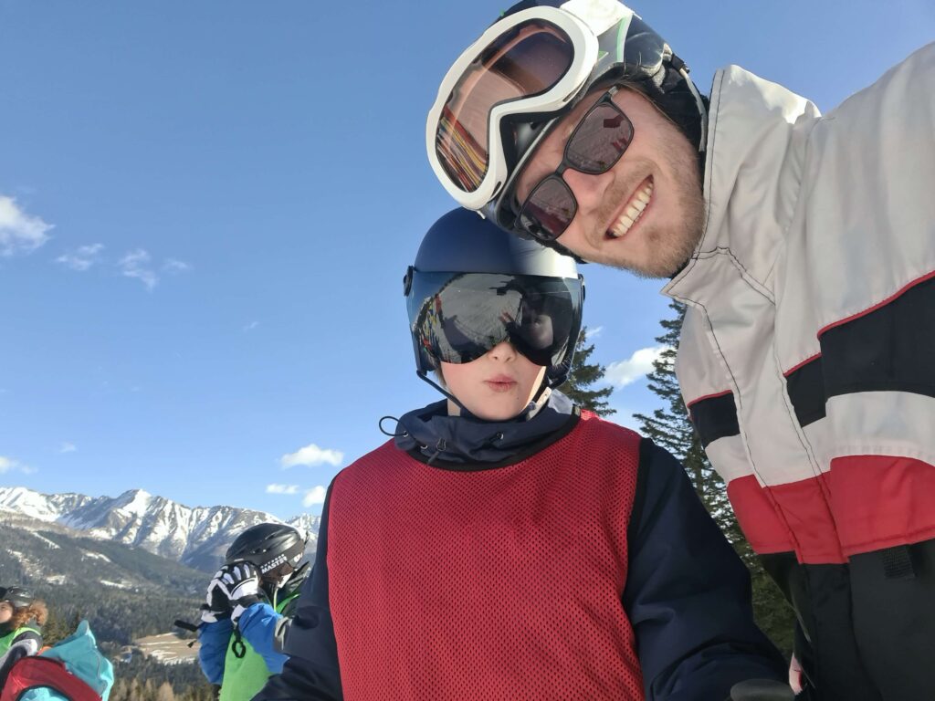 Gruppenszene im Winterferienlager: Kinder und pädagogische Betreuer*innen gemeinsam im Schnee mit Skiern und Schlitten – betreute Kinder- und Jugendreise im Wintercamp Wildfang e.V.