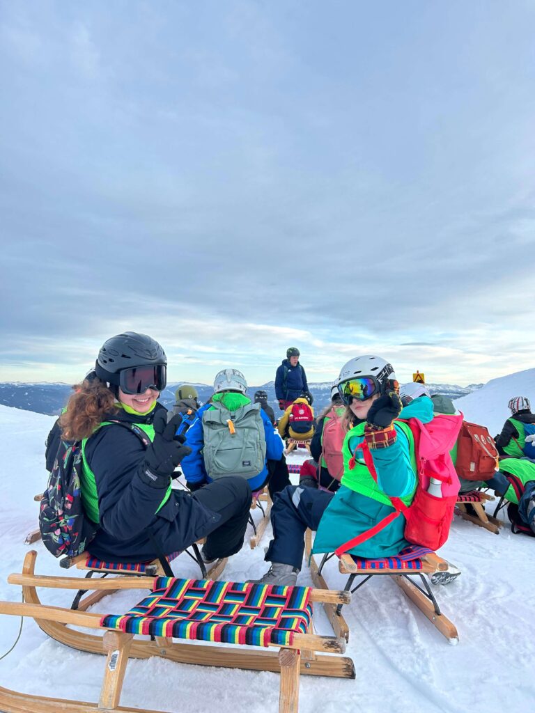Kinder und Betreuer*innen im Winterferienlager von Wildfang e.V. auf der Skipiste mit Skiern und Sonnenschein – betreute Ferienlager-Jugendreise im Schnee