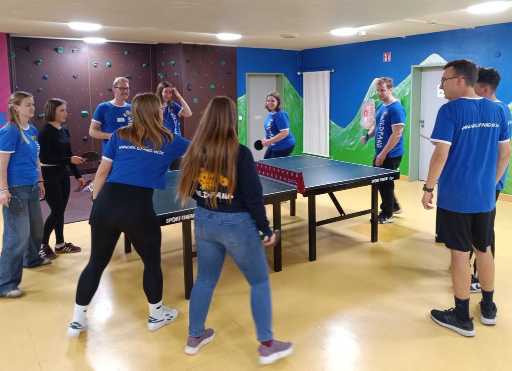 Eine Gruppe von Campleitern spielt gemeinsam Tischtennis in einem Feriencamp